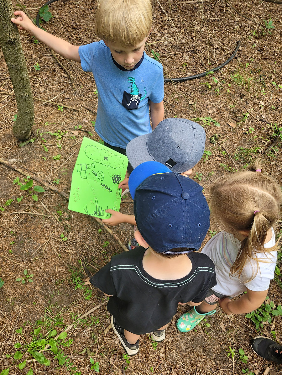 Children gathered around a map while exploring the forest